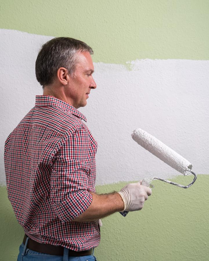Painter rolling a smooth, even finish coat onto an interior wall