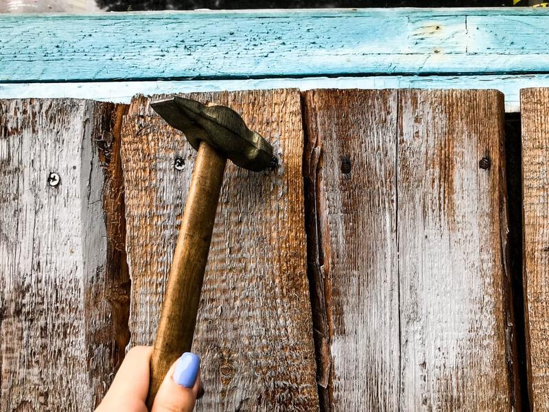 Scraping and sanding failing paint from wooden siding before recoating