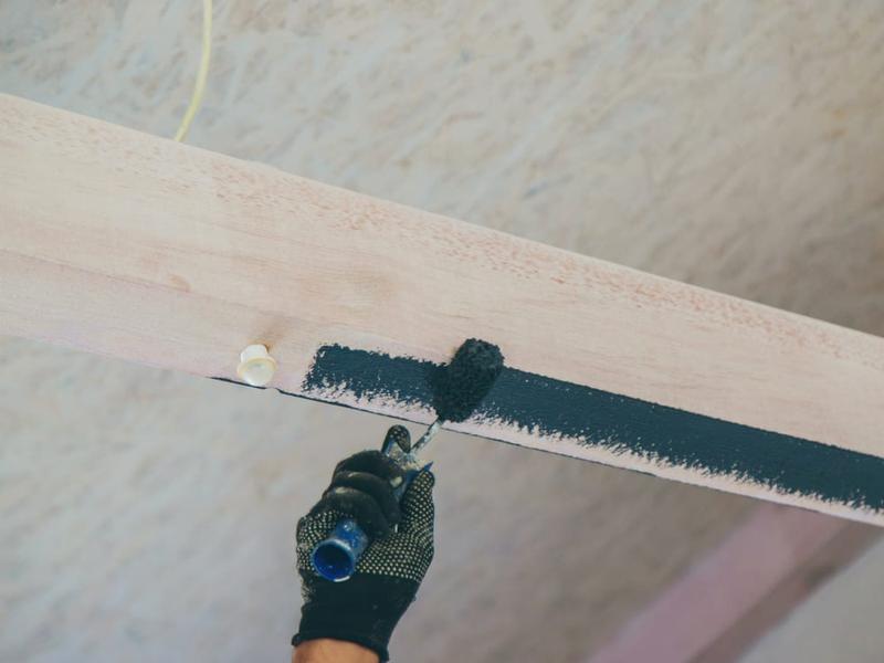 Cutting in a straight line by hand where the wall meets white ceiling trim